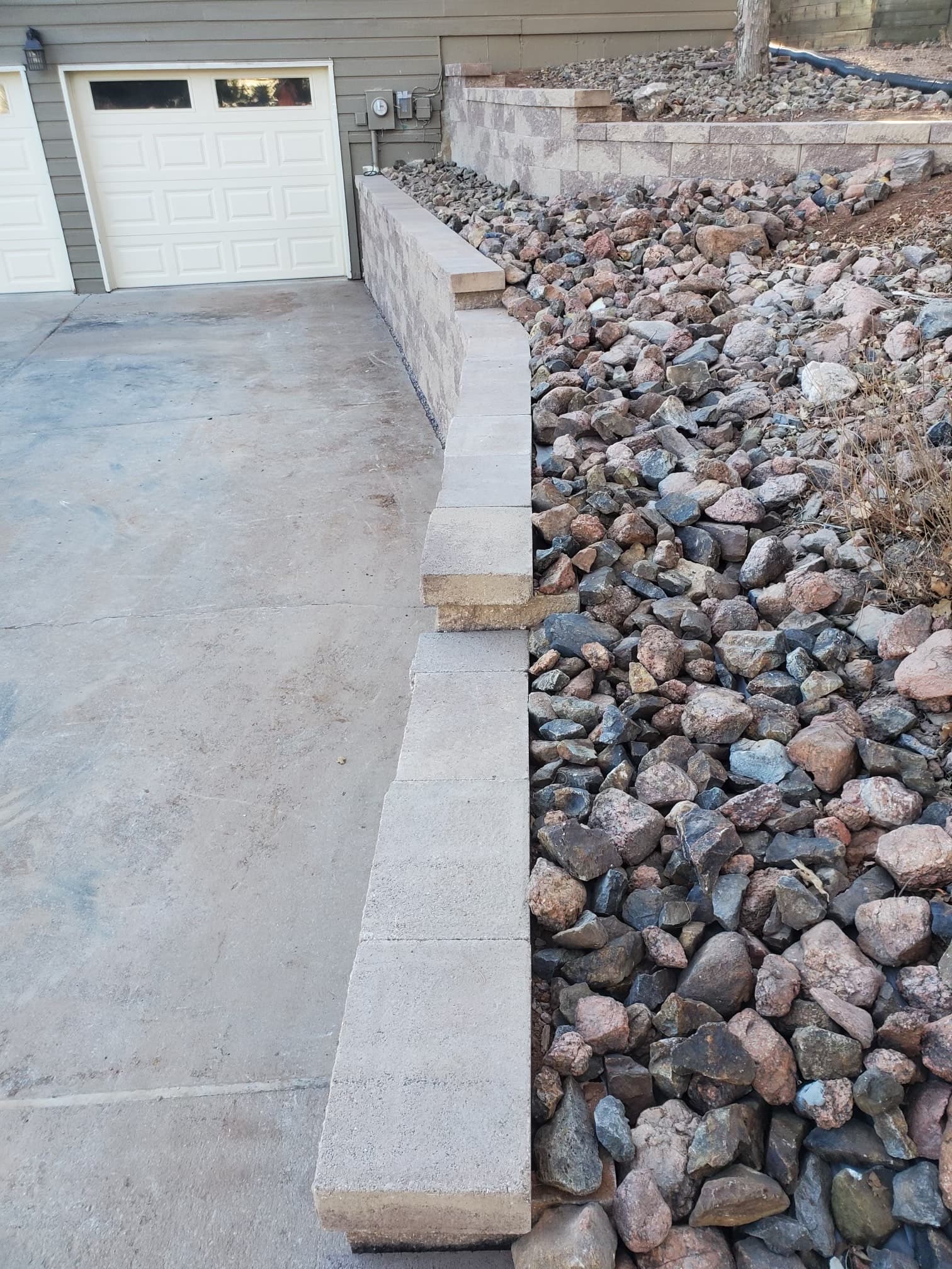 Block retaining wall along driveway with rock fill