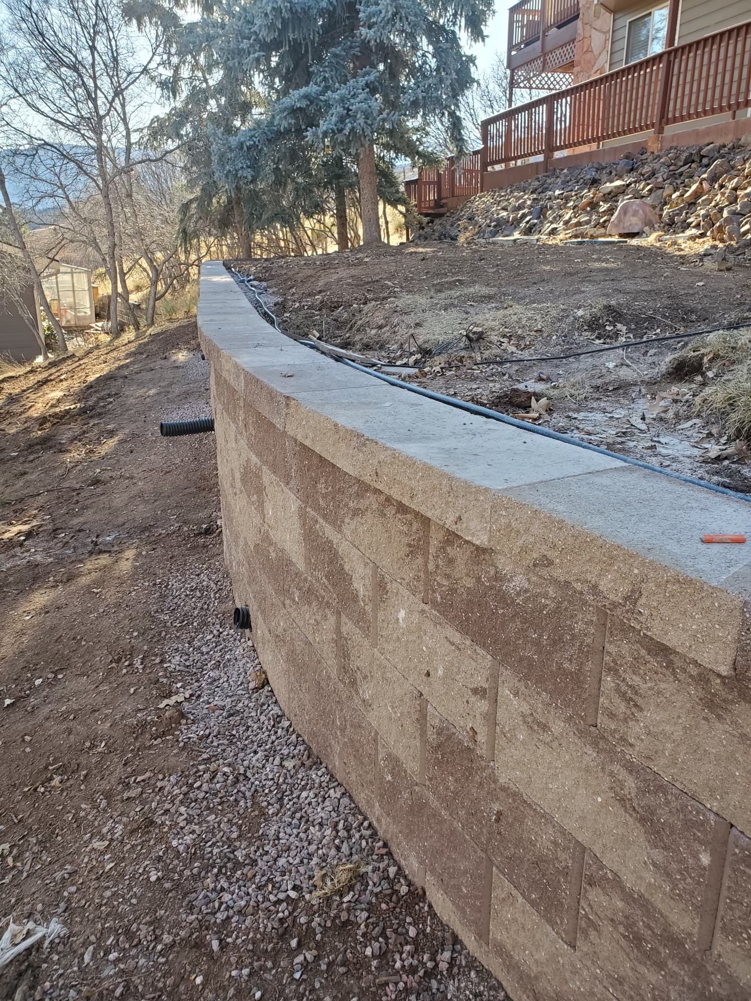 Retaining wall with paver cap along hillside